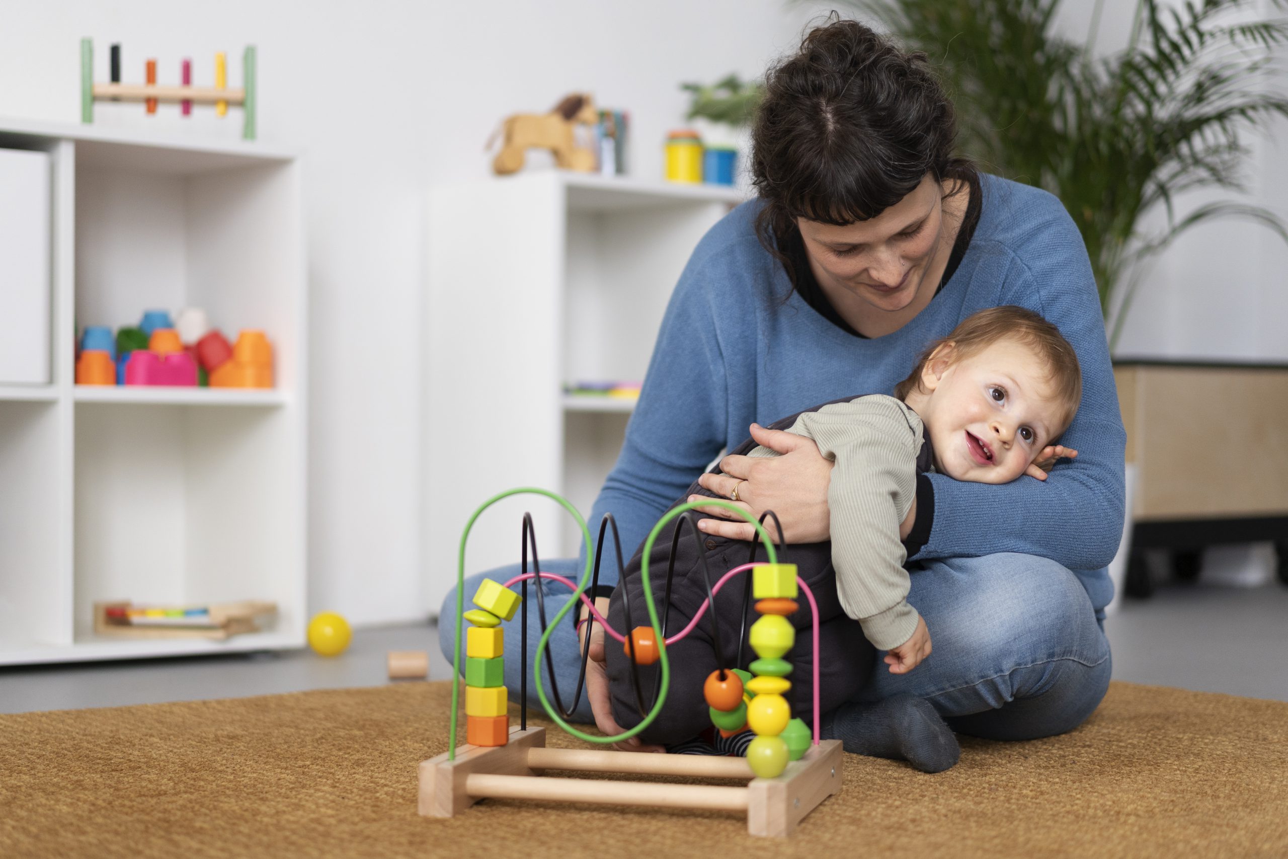 full-shot-smiley-teacher-holding-kid Early Stimulation program